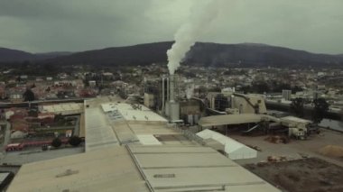 Elektrik üreten bir termik santral. Görüntü, buhar çıkaran bacanın merkezindedir..