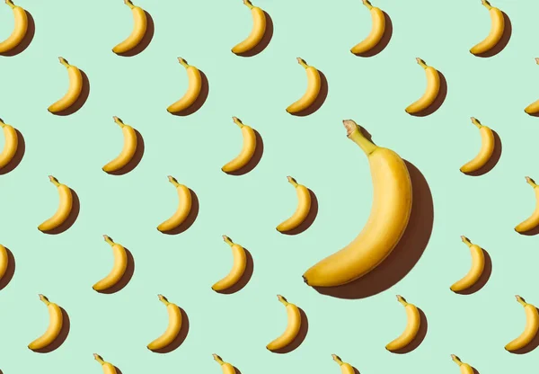 Texture of bananas on a turquoise background, one large banana, a pattern of bananas