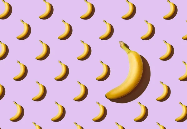Texture of bananas on a purple background, one large banana, a pattern of bananas