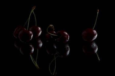 Beyaz arka planda yansımalı kırmızı kirazlar. Siyah arka planda taze kirazlar.