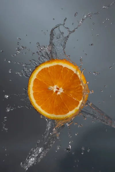 orange in splash of water on a gray background.