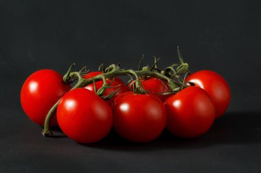 Sapında kiraz domatesleri, siyah arkaplanda kiraz domatesleri.