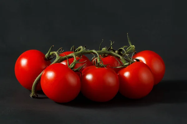 cherry tomatoes on the stem, cherry tomatoes on a black background