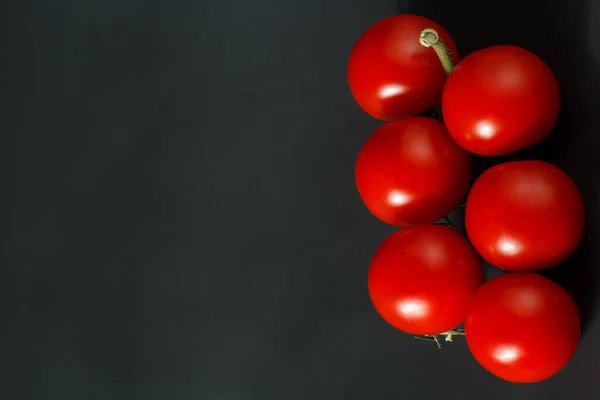 cherry tomatoes on the stem, cherry tomatoes on a black background