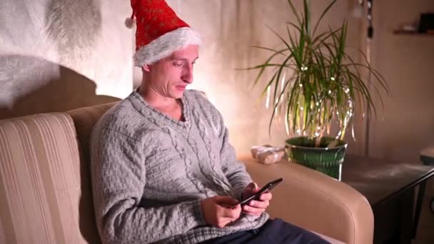 一个男人在网上商店里用智能手机为他的家人和他心爱的女人订了圣诞礼物和新年礼物 网上购物概念 — 图库视频影像