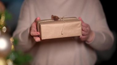 Hediye paketine sarılı kadın elleri. Kadın ellerinde küçük bir hediye. Sığ derinlik ve kutuya odaklanma. Hediye veren kişi, sürpriz. Tatil paketleri, ambalajlar. Mutlu noeller.