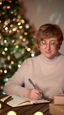 Kadın yılbaşı gecesinde bir dilek listesi yazıyor. Yeni yıl konsepti için yeni yıl planları yapmak ve dilek listesi hazırlamak, kız not defterine yazmak