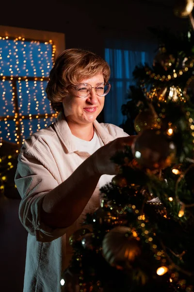 Son sınıf öğrencisi bir kadın Noel gecesinde bir Noel ağacını taşak ve armutla süslüyor. Mutlu Noeller ve yeni yıl geleneği