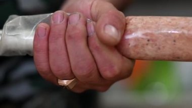 Aile tariflerine göre evde sosis yapıyorlar. Salam ürünü, et endüstrisi, makine. Bir sosis çubuğunu doğal bir kaplama haline getirmek..