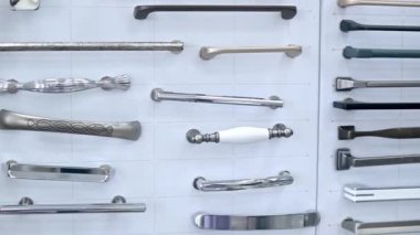 Beyaz bir arka plan vitrinindeki dolapların parçalarından oluşan büyük bir koleksiyon. Ahşap mutfak dolabında farklı paslanmaz çelik saplı metal ve paslanmaz çelik örnekleri var.