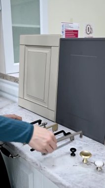 Ev geliştirme konsepti. Tasarımcı kız vitrindeki mobilyaların ön cephelerini ve kollarını seçiyor. Mobilya endüstrisinde dekorasyon tahtaları. Madde örnekleri seçiliyor.