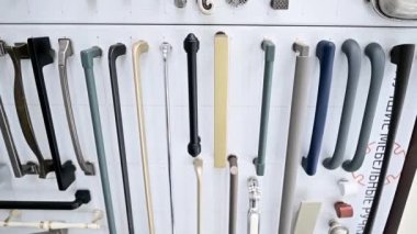 Beyaz bir arka plan vitrinindeki dolapların parçalarından oluşan büyük bir koleksiyon. Ahşap mutfak dolabında farklı paslanmaz çelik saplı metal ve paslanmaz çelik örnekleri var.