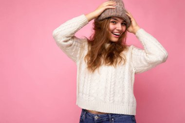 Çekici, gülümseyen, mutlu, esmer kadın renkli arka plan duvarının üzerinde izole bir şekilde dikiliyor. Günlük şık kıyafetler giyiyor ve kameraya bakarak yüz ifadelerini gösteriyor.