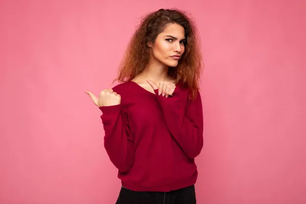 Photo of young beautiful brunette wavy woman with sincere emotions wearing casual pink jersey isolated over pink background with copy space and pointing at free space for mockup — Stock Photo, Image