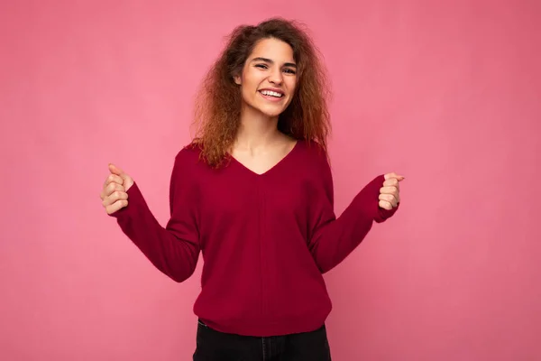 Foto van jong gelukkig glimlachen emotioneel mooi brunette krullend vrouw met oprechte emoties dragen casual roze pullover geïsoleerd over roze achtergrond met kopieerruimte — Stockfoto