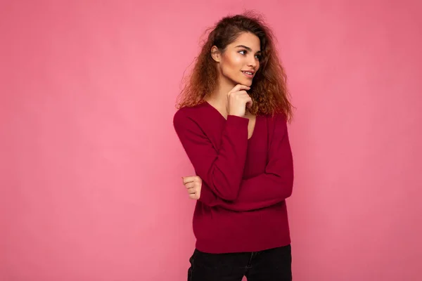 Foto von jungen europäischen nachdenklich faszinierende brünette lockige Frau mit aufrichtigen Emotionen tragen trendigen rosa Pullover isoliert über rosa Hintergrund mit freiem Raum — Stockfoto