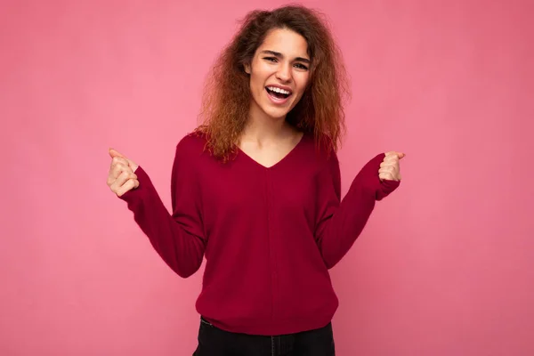 Fénykép a fiatal érzelmi pozitív boldog bájos barna göndör nő őszinte érzelmek visel alkalmi rózsaszín pulóver elszigetelt rózsaszín háttér másolási hely — Stock Fotó