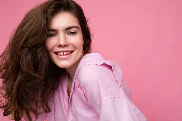 Портрет красивої позитивної веселої милої усміхненої молодої брюнетки в стильній сорочці ізольованої на рожевому фоні з місцем для тексту — стокове фото