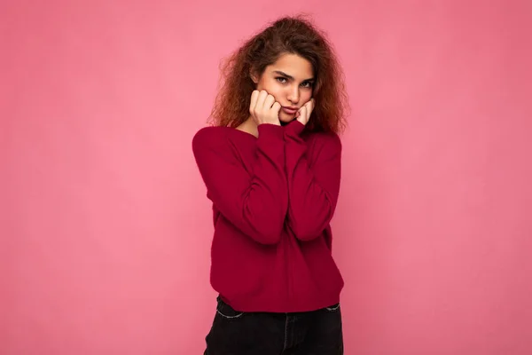 Portrait of young emotional offended touchy beautiful brunette curly woman with sincere emotions wearing trendy pink pullover isolated on pink background with copy space and taking offence — Stock Photo, Image