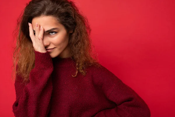 Νεαρή ελκυστική σγουρή μελαχρινή γυναίκα πρόσωπο με ειλικρινή συναισθήματα poising απομονωμένη στον τοίχο φόντο με αντίγραφο χώρου φορώντας casual σκούρο κόκκινο πουλόβερ. Έννοια wtf — Φωτογραφία Αρχείου