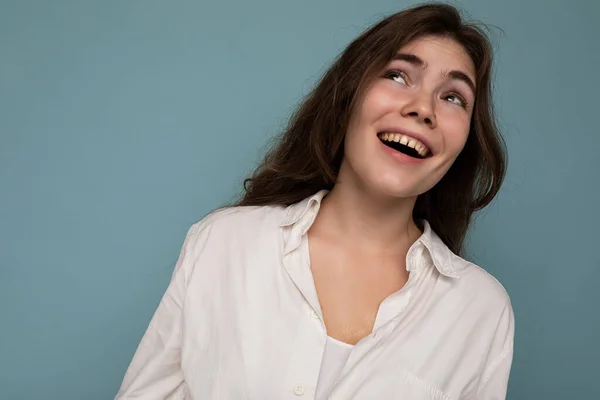 Retrato de belo positivo alegre bonito sorrindo jovem morena na camisa branca casual isolado no fundo azul com espaço de cópia — Fotografia de Stock