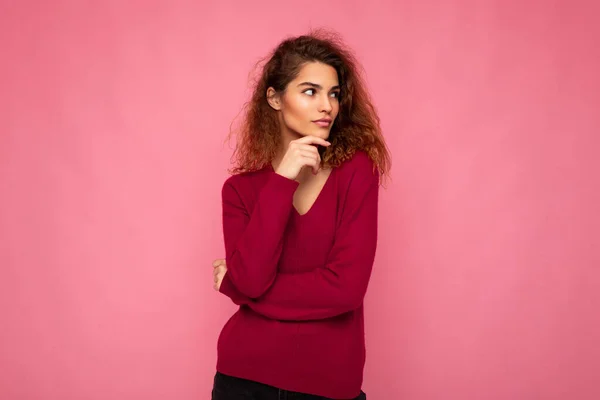 Photo of young european thoughtful charming cute brunette curly woman with sincere emotions wearing trendy pink sweater isolated over pink background with free space — Stock Photo, Image
