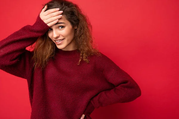 Mladá krásná kudrnatá brunetka žena s upřímnými emocemi balancující izolované na pozadí zdi s kopírovacím prostorem na sobě ležérní tmavě červený svetr. Koncept Wtf — Stock fotografie