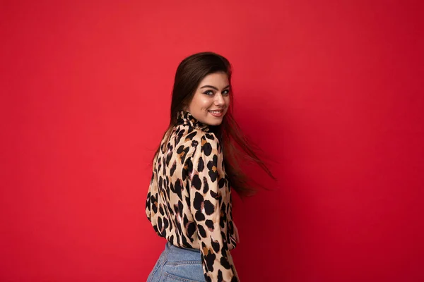 Foto de joven positiva feliz sonriente hermosa mujer morena sexy de moda con elegante blusa de leopardo aislado sobre fondo rojo con espacio vacío — Foto de Stock