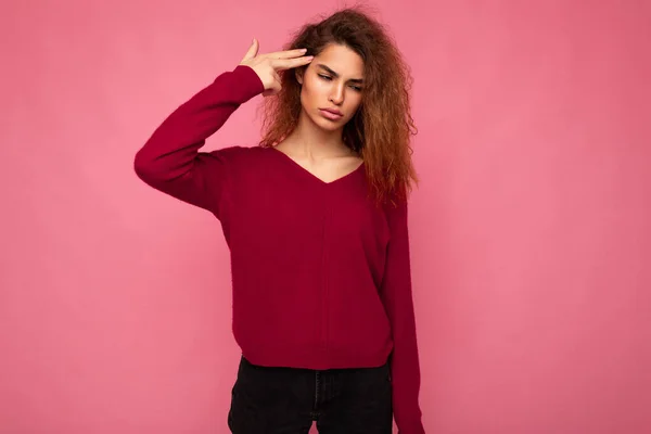 Portrait of young emotional tired beautiful brunette curly woman with sincere emotions wearing trendy pink pullover isolated on pink background with copy space and showing gun gesture with hand — Stock Photo, Image