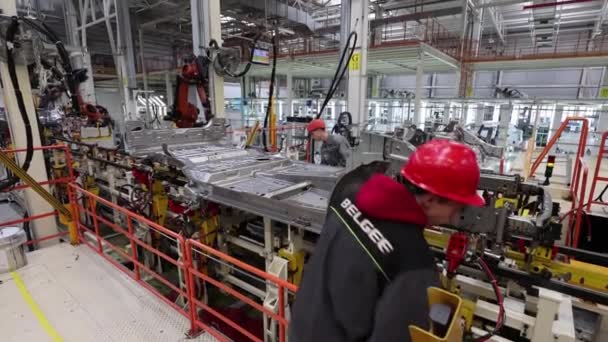 Borisov, Bielorrusia - 29 de octubre de 2021: trabajador en fábrica moderna con sombrero blanco, planta de fabricación de automóviles, seguridad en el trabajo — Vídeos de Stock