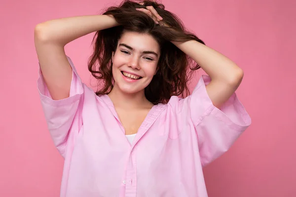 Portrait of beautiful positive cheerful cute smiling young brunette woman in stylish shirt isolated on pink background with copy space — Stock Photo, Image