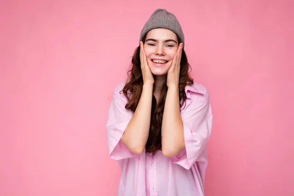 Portrait of beautiful positive cheerful cute smiling young brunette woman in stylish shirt and hipster grey hat isolated on pink background with copy space — Stock Photo, Image