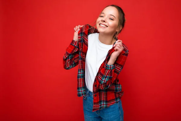 スタイリッシュな赤いヒップスターシャツとモックアップのためのカジュアルな白いTシャツの若い美しい女性。肯定的な女性は顔の感情を示す。フリースペースで赤の背景に隔離された面白いモデル — ストック写真