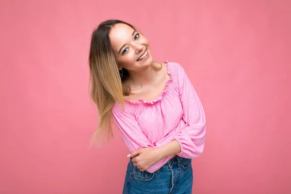 화려 한 분홍색 작물의 윗부분 블라우스를 입은, 아름답게 웃는 젊은 금발 여자의 모습. 섹시하고 태평 한 여성 이 스튜디오의 핑크 벽 근처에 고립되어 있습니다. 자연 화장을 한 양성 모델. 복사 — 스톡 사진