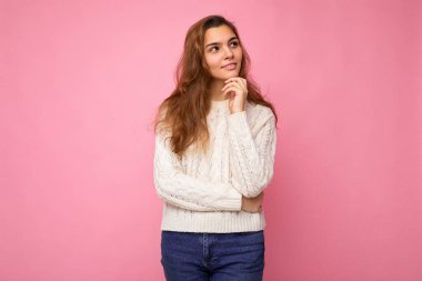 Moda kıyafetleri içinde genç ve çekici beyaz bir kadın. Seksi kaygısız kadın stüdyoda izole edilmiş pembe duvar pozu veriyor. Doğal makyajlı düşünceli bir rüya modeli. Boş boşluk