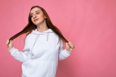 Çekici, mutlu, günlük kıyafetler giyen, renkli arka planda tek başına duran genç bir kadının görüntüsü.