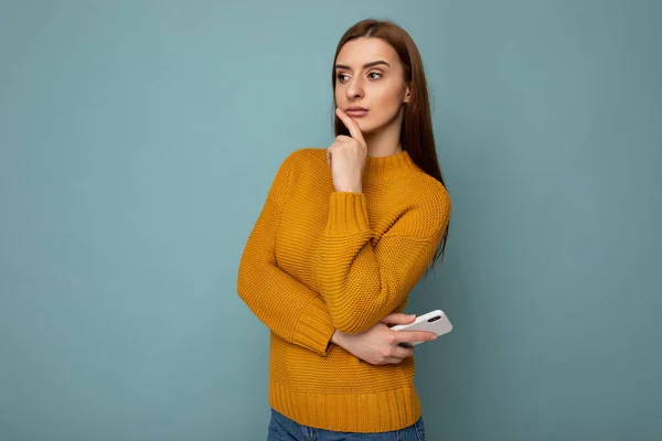 Zdjęcie młodej, troskliwej, atrakcyjnej brunetki ze szczerymi emocjami w musztardowym pulowerze odizolowanej na niebieskim tle z pustą przestrzenią i myśleniem — Zdjęcie stockowe