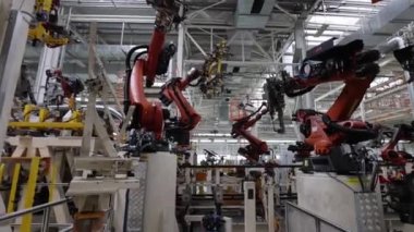 Robotlar parçalarını modern bir fabrikada araba gövdesine yerleştirir ve kaynak yaparlar.
