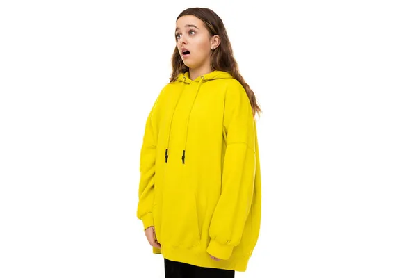 Foto di bella scioccato sorpreso bruna adolescente in elegante felpa sportiva gialla su sfondo bianco con spazio libero per il testo — Foto Stock