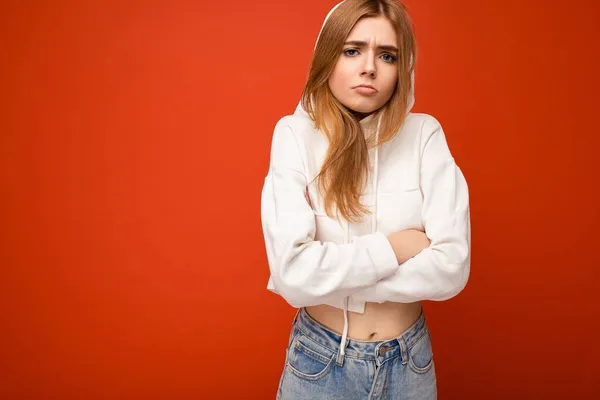 Insatisfecho joven enojado hermosa rubia oscura persona femenina con emociones sinceras aisladas en la pared de fondo con espacio de copia para el texto con capucha blanca casual. Concepto negativo — Foto de Stock