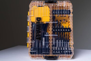 Arka planda sondaj delikleri ve metin için fotokopi alanı ile izole edilmiş tornavida için matkaplarla birlikte turuncu ve şeffaf kit kutusunun fotoğraf çekimi. Araçlar kümesi