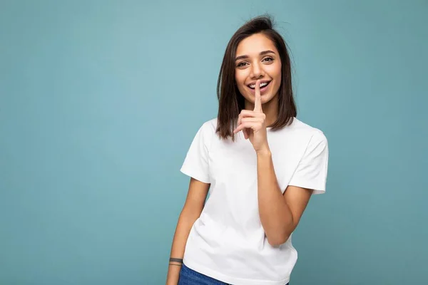 Foto av positiva glada leende ung fascinerande vacker attraktiv trevlig brunett kvinna med uppriktiga känslor bär casual vit t-shirt för mockup isolerad över blå bakgrund med kopia utrymme — Stockfoto