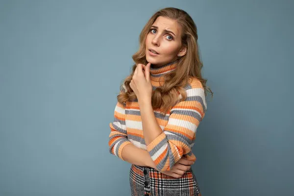 Portrait photo of young pretty beautiful attractive sad unhappy blonde woman with wavy-hair wearing striped sweater isolated over blue background with empty space for text — Stock Photo, Image