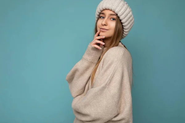 Foto von attraktiven charmanten niedlich schön positiv glücklich lächelnde junge dunkelblonde Frau isoliert über blauem Hintergrund mit Kopierraum trägt beige warmen Pullover und gestrickte beige Mütze — Stockfoto