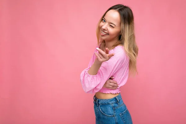 Foto shot van jong mooi schattig gelukkig blond vrouw dragen stijlvolle roze gewas top geïsoleerd over roze achtergrond met kopieerruimte — Stockfoto