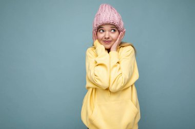 Güzel, pozitif, mutlu, genç, sarışın bir kadın. Renkli arka plan duvarından izole edilmiş, günlük, şık kıyafetler giymiş, samimi duygular besliyor.