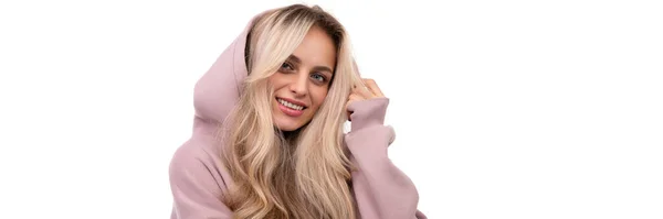 Foto widescreen de uma loira com um sorriso no rosto em um traje rosa e um capuz — Fotografia de Stock