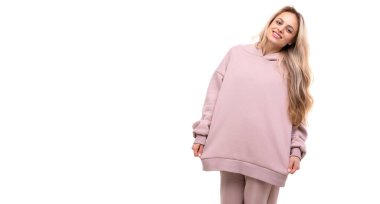 Yüzünde pembe kapüşonlu beyaz bir arka planda gülümseyen bir sarışın.