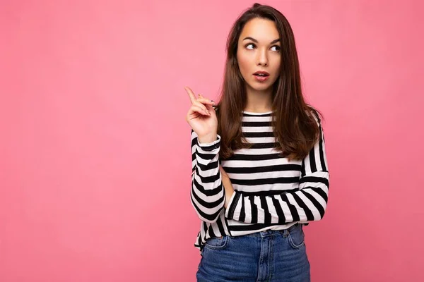 Photo of young european positive thinking and dreaming beautiful brunette woman with sincere emotions wearing casual striped pullover and having an idea isolated on pink background with copy space for — Stock Photo, Image