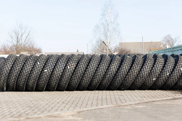 Foto de neumáticos grandes negros sobre ruedas para coches grandes que yacen sobre asfalto gris en la calle — Foto de Stock